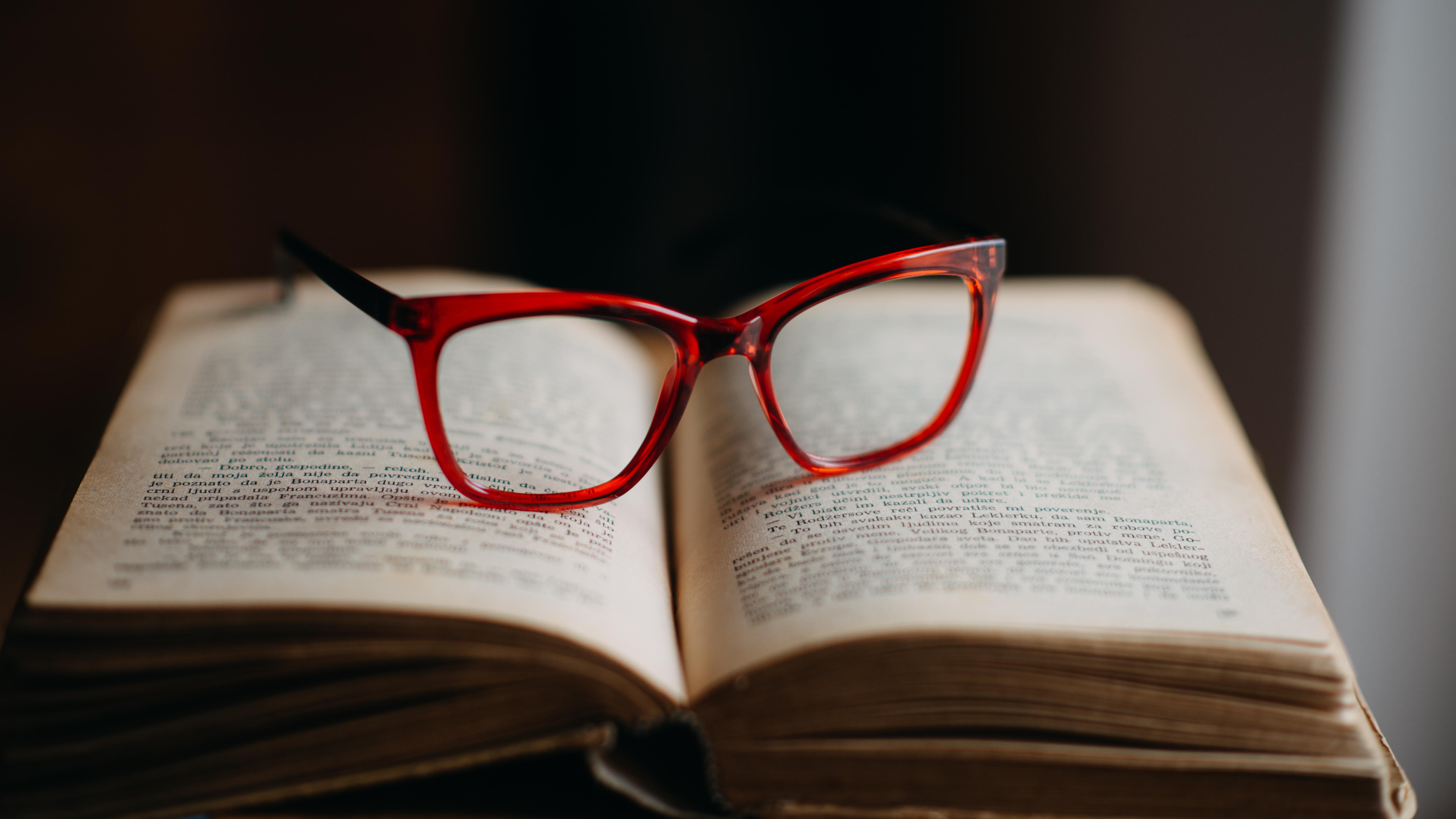 Modern red glasses on old book closeup